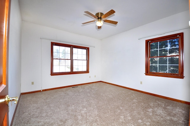 carpeted empty room featuring ceiling fan and baseboards