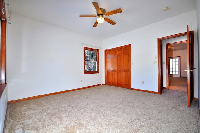 unfurnished bedroom featuring carpet floors, a closet, visible vents, ceiling fan, and baseboards