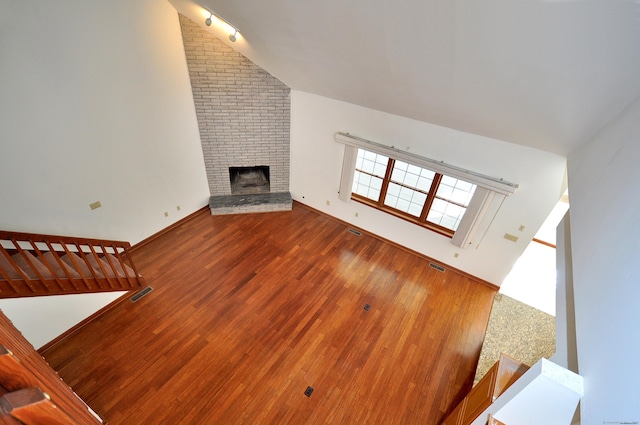 unfurnished living room with a fireplace, wood finished floors, visible vents, and baseboards