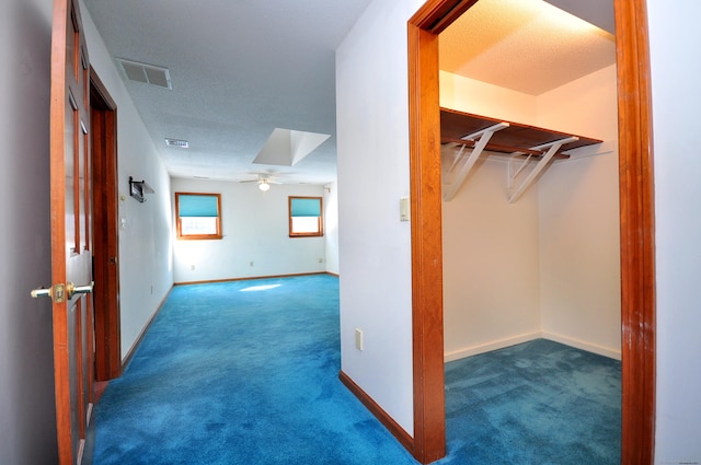 hallway with carpet, visible vents, and baseboards