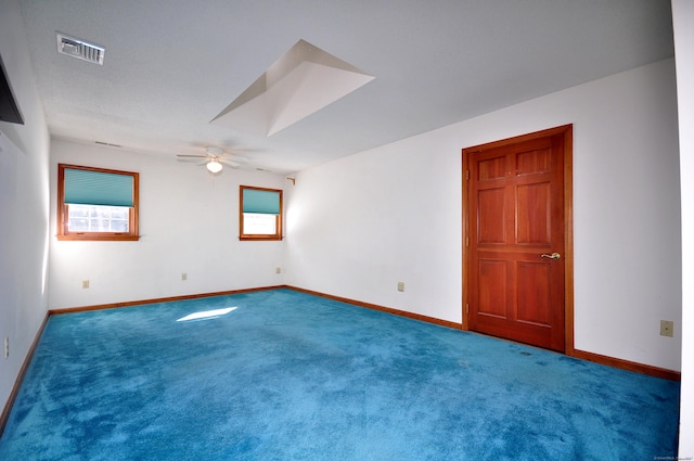 carpeted empty room with a ceiling fan, a skylight, visible vents, and baseboards