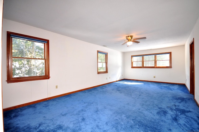 carpeted spare room featuring ceiling fan and baseboards