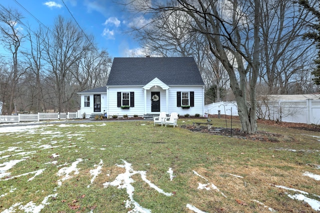 view of front of home with a shingled roof, a front yard, and fence