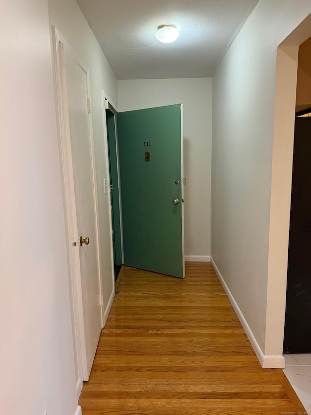 corridor with light wood finished floors and baseboards