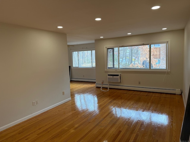 spare room with a wall unit AC, a baseboard heating unit, wood finished floors, and recessed lighting