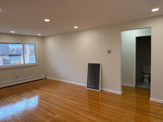 empty room with baseboards, baseboard heating, wood finished floors, and recessed lighting