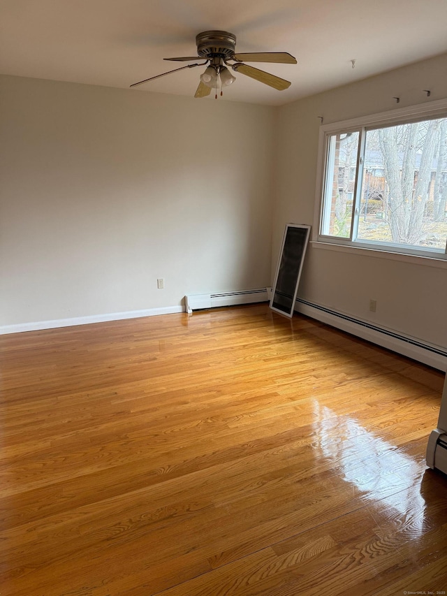 unfurnished room with a baseboard heating unit, ceiling fan, baseboards, and light wood-style floors