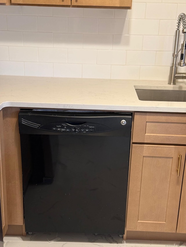 interior details featuring black dishwasher, light countertops, a sink, and decorative backsplash