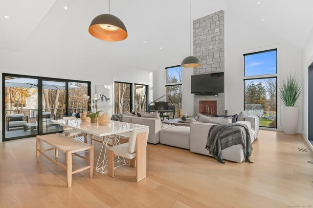 dining room featuring high vaulted ceiling, a fireplace, and light wood-style floors