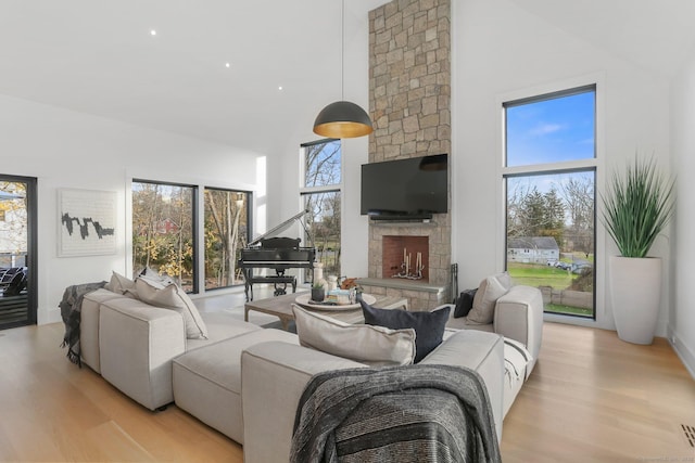 living area with light wood-style floors, a fireplace, and a towering ceiling