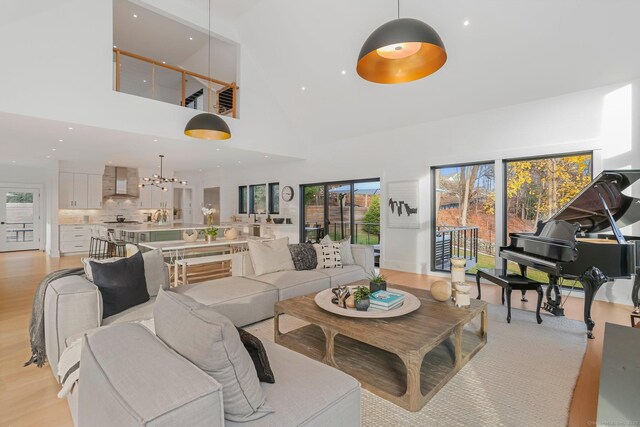 living area featuring light wood-style floors, a high ceiling, a chandelier, and recessed lighting