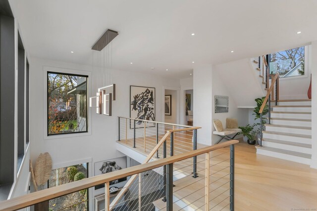 corridor with stairs, recessed lighting, a wealth of natural light, and light wood-style floors