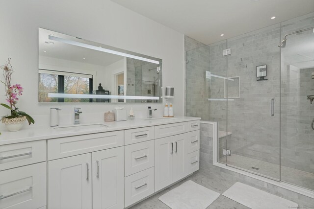 full bath featuring double vanity, a stall shower, and a sink