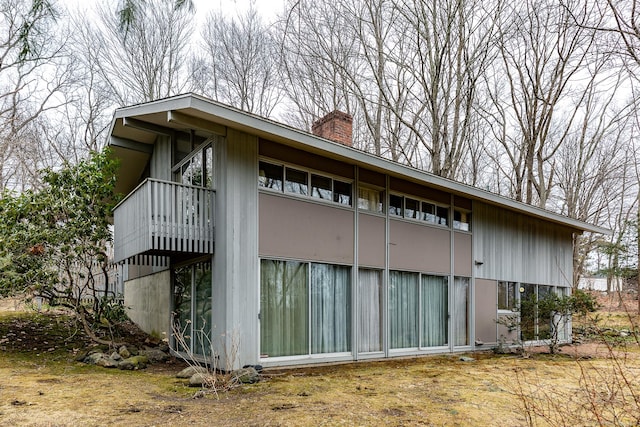 view of side of property featuring a chimney and a balcony