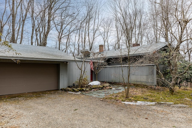 view of home's exterior with a garage, driveway, and a chimney