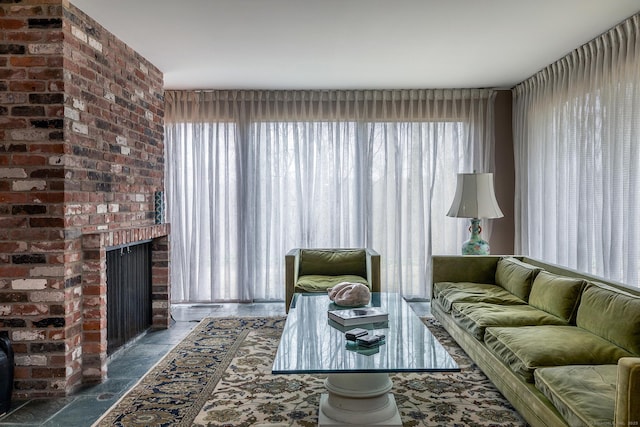 living room with stone finish flooring, plenty of natural light, and a brick fireplace