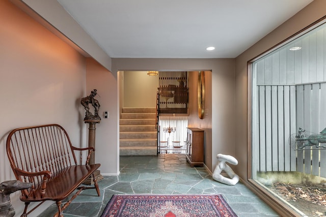 sitting room featuring stairs, baseboards, stone tile flooring, and recessed lighting