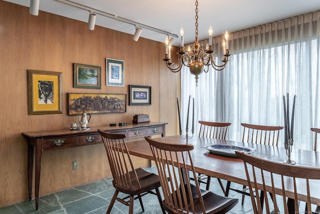 dining area featuring an inviting chandelier and wooden walls