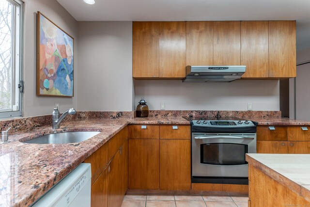 kitchen with brown cabinets, stainless steel range with electric cooktop, a sink, dishwasher, and exhaust hood