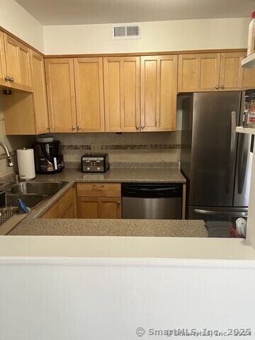 kitchen with visible vents, backsplash, appliances with stainless steel finishes, a sink, and a peninsula