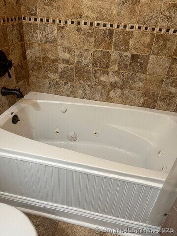 full bath with toilet and a whirlpool tub