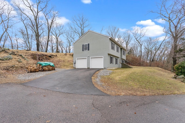 view of home's exterior featuring a garage, a yard, and driveway