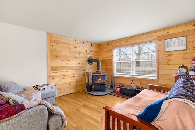 living area with wood finished floors, a wood stove, and wooden walls