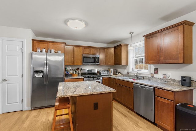 kitchen featuring appliances with stainless steel finishes, light wood-style floors, a sink, and a kitchen island