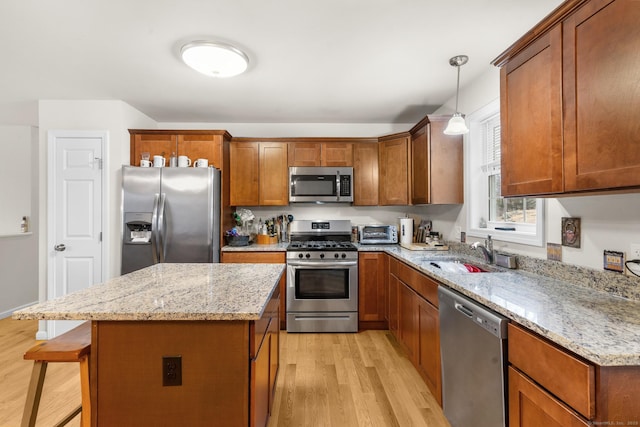 kitchen with stainless steel appliances, a sink, light wood finished floors, and light stone countertops