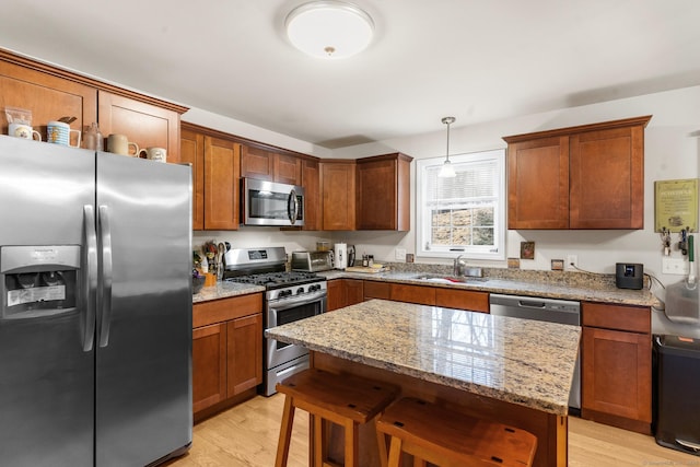 kitchen with light wood-type flooring, light stone countertops, stainless steel appliances, and a sink