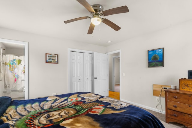 bedroom with a closet, a ceiling fan, light carpet, ensuite bath, and baseboards