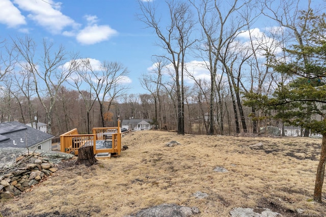 view of yard featuring a forest view and a wooden deck