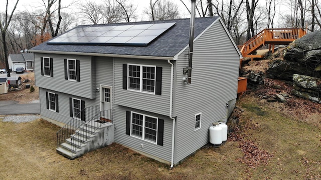 exterior space featuring solar panels and roof with shingles