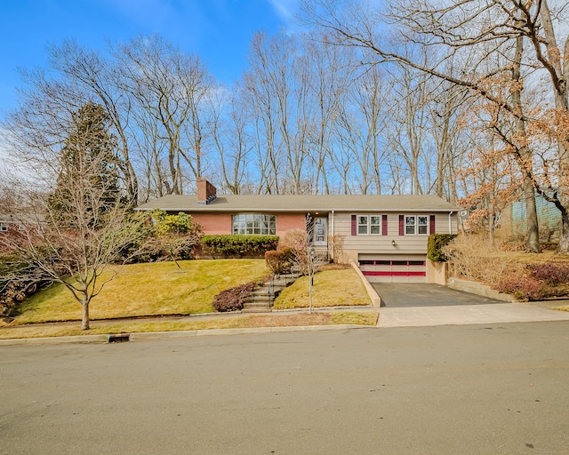 view of front facade featuring a garage, a front yard, driveway, and a chimney