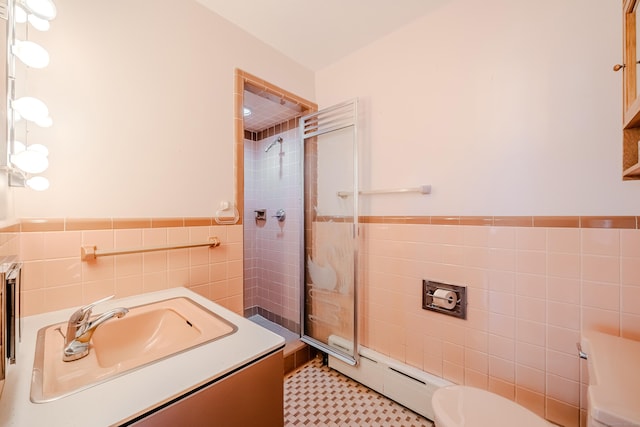 bathroom featuring a baseboard heating unit, tile walls, toilet, and vanity