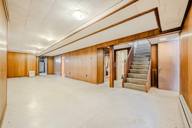 finished basement featuring wood walls, fridge, stairs, and a baseboard heating unit