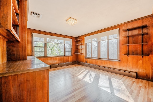 interior space featuring visible vents, built in features, a baseboard radiator, wood finished floors, and wood walls