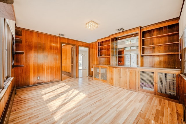 unfurnished living room with wood walls, visible vents, and wood finished floors