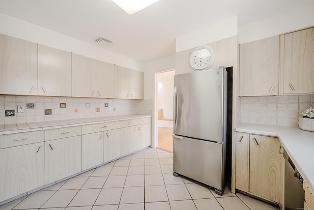 kitchen featuring appliances with stainless steel finishes, light tile patterned flooring, visible vents, and decorative backsplash