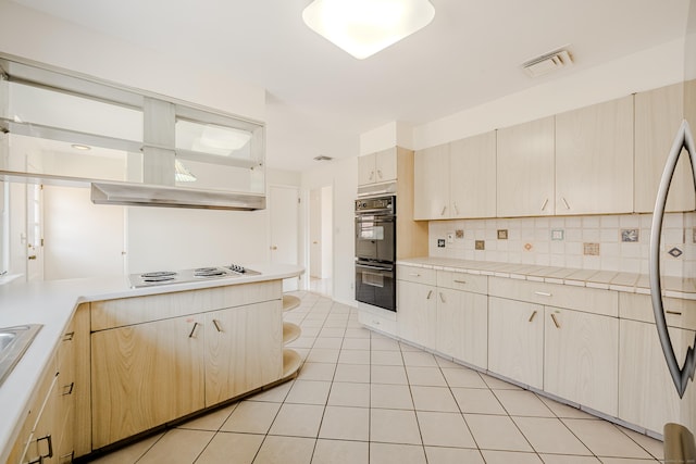 kitchen featuring light tile patterned floors, tasteful backsplash, visible vents, dobule oven black, and electric stovetop