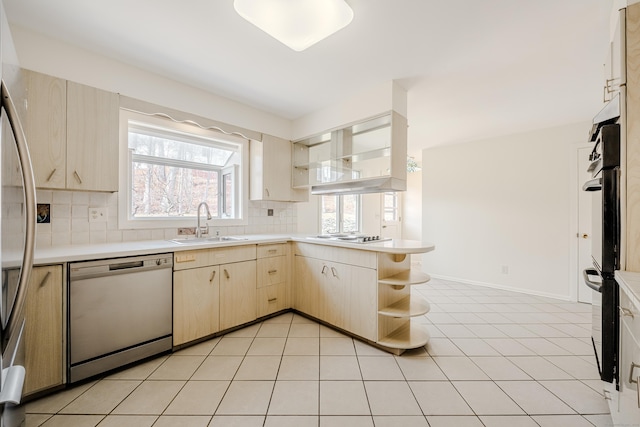 kitchen featuring open shelves, backsplash, appliances with stainless steel finishes, light brown cabinets, and a sink