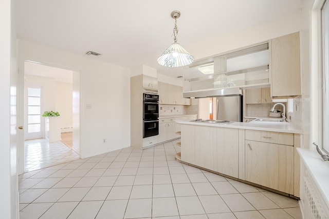 kitchen with light tile patterned floors, a peninsula, a sink, visible vents, and light countertops