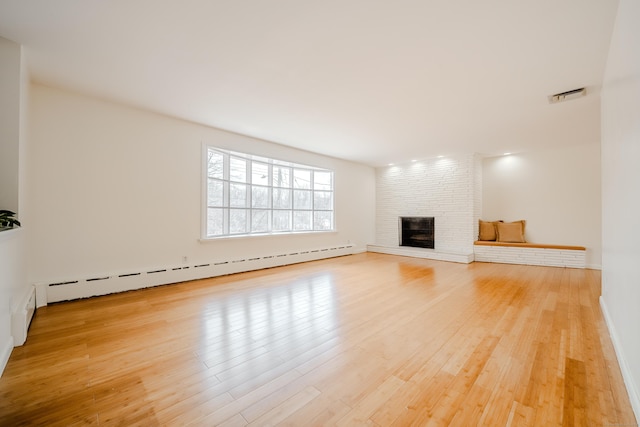 unfurnished living room with a baseboard radiator, visible vents, a fireplace, and light wood finished floors