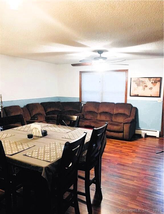 dining space featuring ceiling fan, a textured ceiling, baseboard heating, and wood finished floors