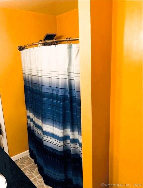 bathroom with curtained shower and baseboards