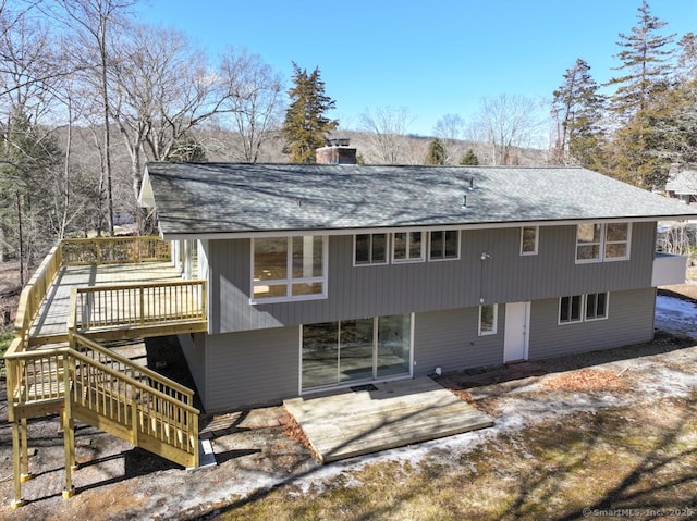 back of property featuring a chimney, roof with shingles, stairs, a wooden deck, and a patio area