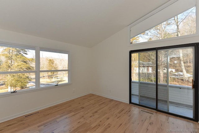 unfurnished room with light wood-style floors, visible vents, vaulted ceiling, and baseboards