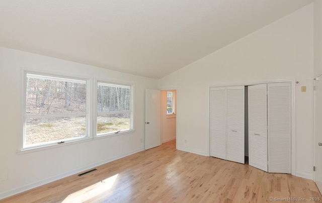 unfurnished bedroom with vaulted ceiling, visible vents, and light wood-style floors