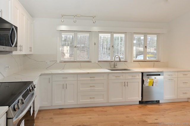 kitchen with a wealth of natural light, appliances with stainless steel finishes, a sink, and white cabinetry