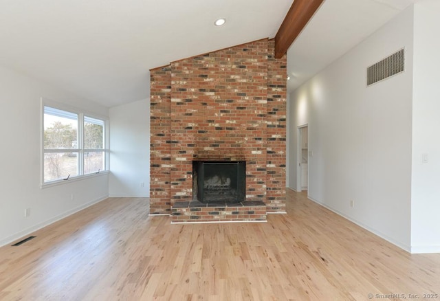 unfurnished living room with a brick fireplace, visible vents, lofted ceiling with beams, and wood finished floors